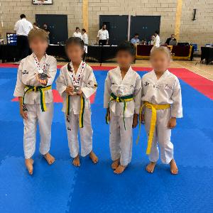Four young students on the competition mat with medals