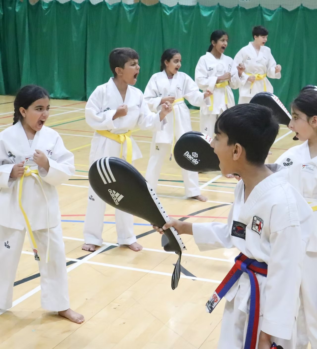 Young students in dobok training with kick pads at London Taekwondo Panthers